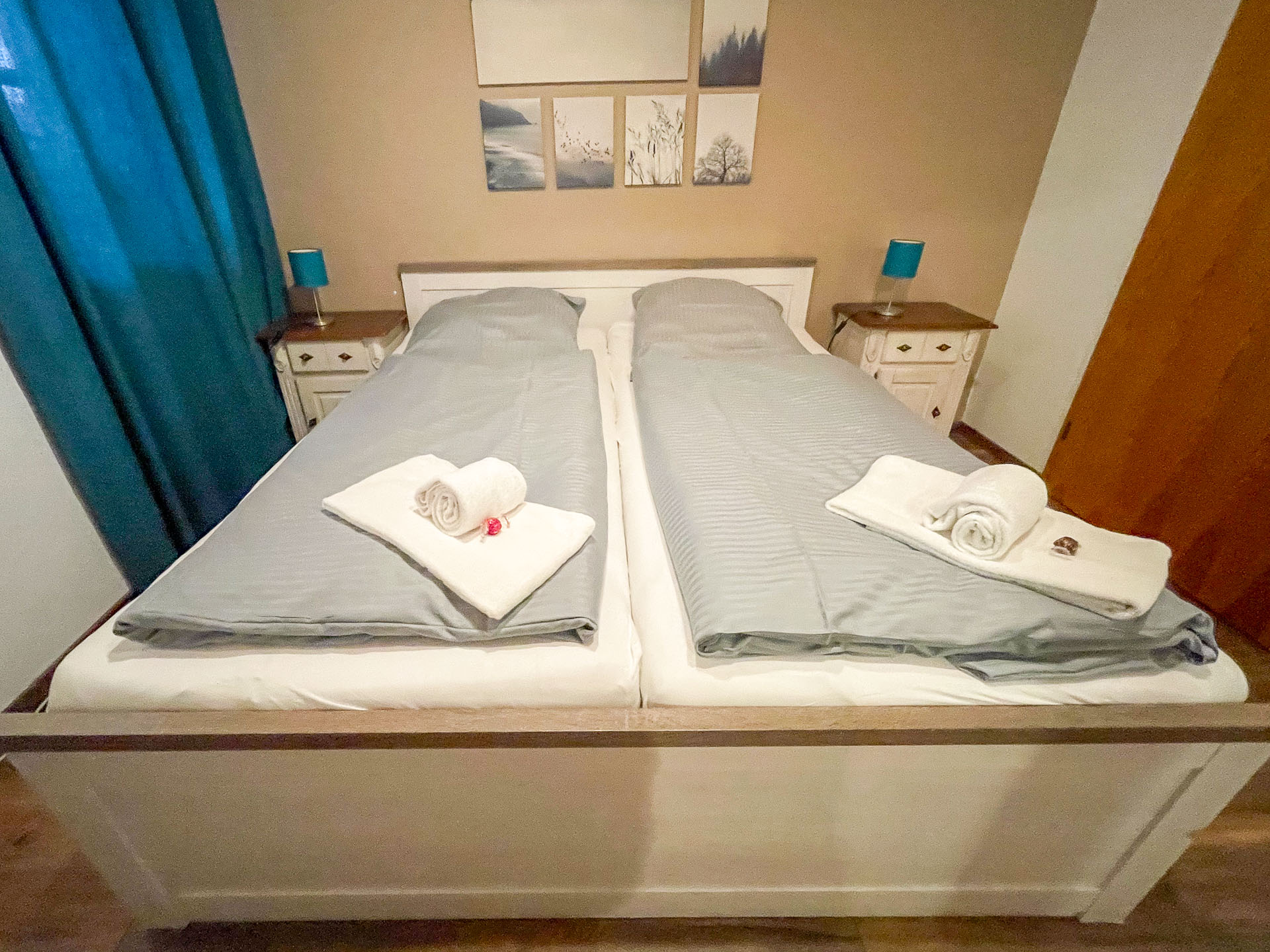 Das komfortable Doppelbett mit separaten Matratzen sorgt für höchsten Schlafkomfort. Frisch bezogene Bettwäsche und Handtücher stehen für Sie bereit. Stilvolle Nachttische mit modernen Lampen und warme Farbtöne verleihen dem Raum eine einladende Atmosphäre.